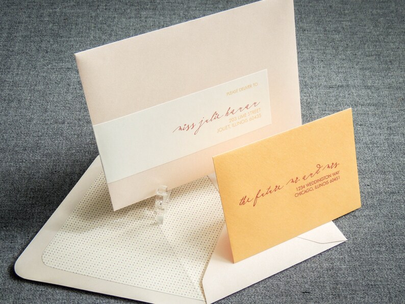 May include: Two envelopes, one pink and one orange, with handwritten addresses. The pink envelope has the text "Please Drama To" and "Miss Jela Berar" with the address "200 Lake Street,  Jouet, Illinois 60451". The orange envelope has the text "The Future Mr. & Mrs." with the address "1234 Weddington Way, Chicago, Illinois 60451".