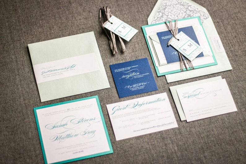 May include: Wedding invitation suite with teal and navy blue accents. The invitation features the names "Sarah Stevens" and "Matthew Gray" in elegant calligraphy. The RSVP card says "Reception".