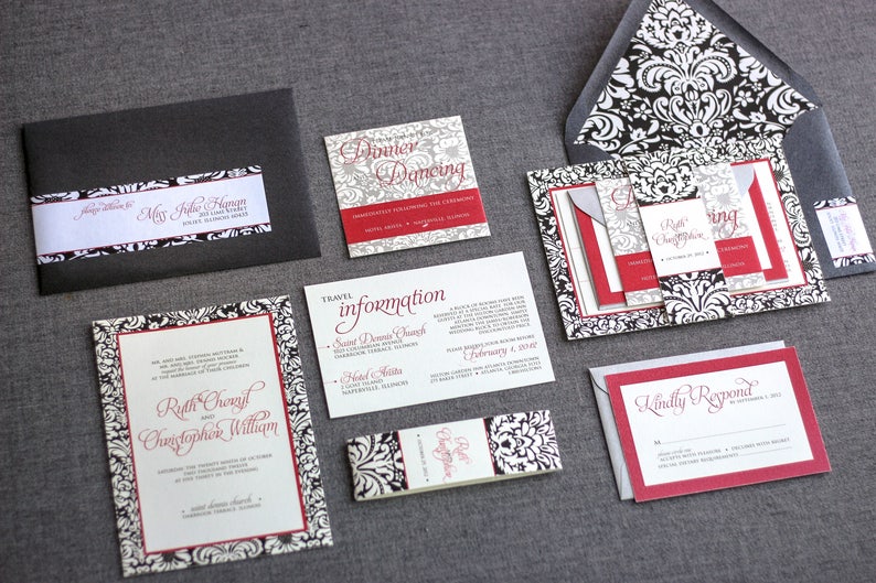 May include: Black and white damask patterned wedding invitation suite with red accents. The invitation includes the names Ruth Cronyn and Christopher William, the date February 1, 2014, and the location Saint Dennis Church. The RSVP card says "Kindly Respond".
