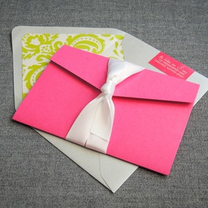 Pode incluir: Um envelope rosa com uma fita branca e um envelope branco com um padr&atilde;o verde e branco. O envelope rosa tem um r&oacute;tulo de endere&ccedil;o de retorno com o texto "Julie & Mike 123 Weddington Way Chicago, Illinois 60641".
