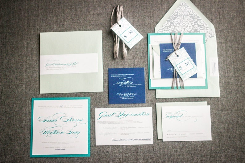 May include: A wedding invitation suite with a teal and navy blue color scheme. The invitation features the names "Sarah Stevens" and "Matthew Gray" in elegant calligraphy. The RSVP card includes the text "Reception" and the date and location of the reception. The envelope is a light teal color with a white damask pattern.