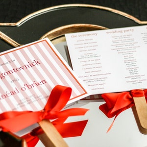 May include: Wedding ceremony program fans with pink and white striped covers and red ribbon bows. The front cover reads "The Marriage of David Gontovnick and Sin&eacute;ad O'Brien".