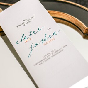 May include: A white wedding ceremony programme with the names "Elaine Price" and "Joshua Flowers" in teal and orange text. The date and location of the ceremony are listed below the names.