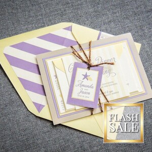 May include: A purple and yellow striped envelope with a beige invitation card featuring a starfish design and the text "Amanda and Jason" with a date. The invitation card is tied with twine and a tag that says "Cocktail Dinner" and "Continuing on the Evening".