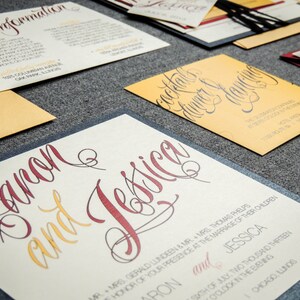 May include: Wedding invitation suite with a cream background and burgundy and gold lettering. The invitation reads "Aaron and Jessica" with the date and time of the wedding.
