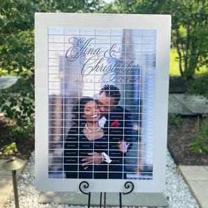 Könnte beinhalten: Ein weißes Schild mit einem Gittermuster und einem Foto eines Paares. Das Schild zeigt "Afina & Christopher June 24, 2023".