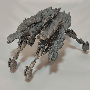 May include: A gray, geometric model of a futuristic vehicle or spacecraft. The model has a complex, textured surface and multiple articulated legs or appendages. The design suggests a science fiction or fantasy theme.