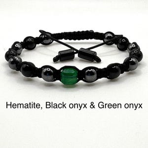 May include: Adjustable bracelet featuring black onyx and hematite beads, with a central green onyx bead. The bracelet is strung on a black cord and includes the text "Hematite, Black onyx & Green onyx".