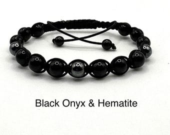 May include: Black onyx and hematite beaded bracelet. The bracelet features black onyx beads and silver hematite beads. The bracelet has a black adjustable cord. The text "Black Onyx & Hematite" is below the bracelet.