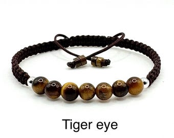 May include: A brown macrame bracelet featuring tiger eye beads. The bracelet has a woven band and adjustable closure. The text "Tiger eye" is displayed below the bracelet.