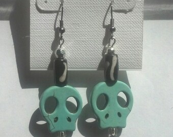Light blue skull sitting on clear bead with black and white swirl bead wire dangle handmade earring