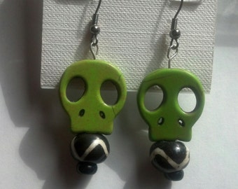 Light green skull sitting on a black and white bead dangle wire earring.