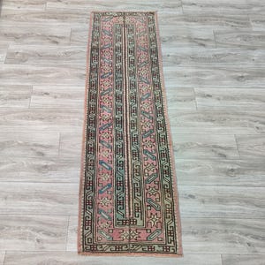 May include: A long, narrow rug with a traditional Turkish design. The rug is pink, green, and blue with intricate patterns.