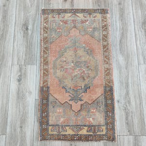 May include: A vintage-style rug with a faded pink and blue colour scheme. The rug has a traditional Persian design with intricate details and a central medallion.