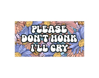 Peut inclure: Autocollant rectangulaire avec un fond floral aux tons pêche, bleu et jaune. Le texte blanc, bordé de noir, dit "PLEASE DON'T HONK I'LL CRY". Un design floral et un message humoristique.