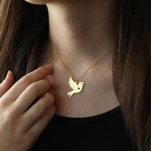 Puede incluir: Un collar de oro con un delicado colgante de paloma con un peque&ntilde;o coraz&oacute;n recortado. La paloma es un s&iacute;mbolo de paz y amor.