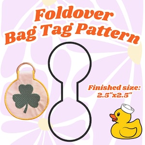 May include: A pattern for a foldover bag tag with the text "Foldover Bag Tag Pattern". The finished size is 2.5" x 2.5". Includes a shamrock bag tag, a duck wearing a sailor hat, and a black outline of the bag tag.