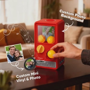 May include: A red custom photo and mini vinyl machine with a clear window displaying a couple's photo. The machine has yellow knobs and yellow gumball-like objects. The text "Custom Photo Background" and "Custom Mini Vinyl & Photo" are visible.