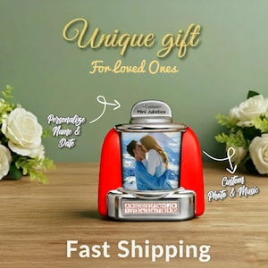 May include: A red and silver mini jukebox with a photo of a couple kissing. The jukebox has a silver top and base, with a red body. The text "Unique gift For loved Ones" is at the top. The text "Personalize Name & Date" is on the left.
