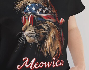 May include: Black t-shirt featuring a detailed illustration of a cat wearing sunglasses and a headband with the American flag design. The word "Meowica" is written in a stylized font below the cat image. The cat has brown and tan fur.