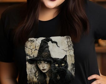 May include: Black t-shirt featuring a graphic of a witch with a black cat. The witch is wearing a pointed hat. The image has a vintage, slightly distressed look. The background includes a shelf with candles and pumpkins, creating a Halloween theme.