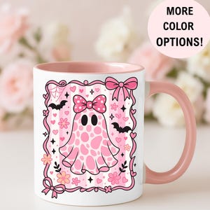 ceramic coffee mug featuring a pink spotted ghost with a bow, surrounded by bats, hearts, and flowers in a coquette aesthetic design