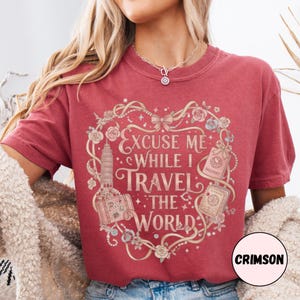 Vintage-inspired pink and beige travel-themed shirt with passport, suitcase, and the quote “Excuse Me While I Travel The World” framed in florals.