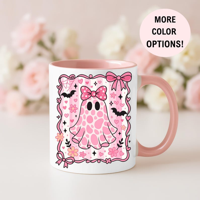 ceramic coffee mug featuring a pink spotted ghost with a bow, surrounded by bats, hearts, and flowers in a coquette aesthetic design