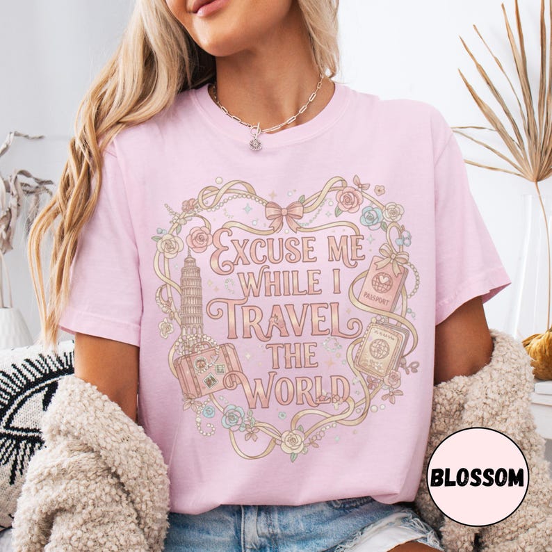 Vintage-inspired pink and beige travel-themed shirt with passport, suitcase, and the quote “Excuse Me While I Travel The World” framed in florals.
