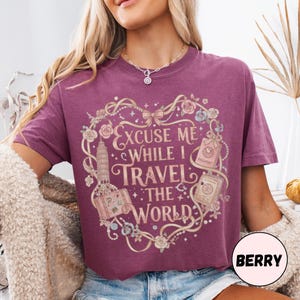 Vintage-inspired pink and beige travel-themed shirt with passport, suitcase, and the quote “Excuse Me While I Travel The World” framed in florals.