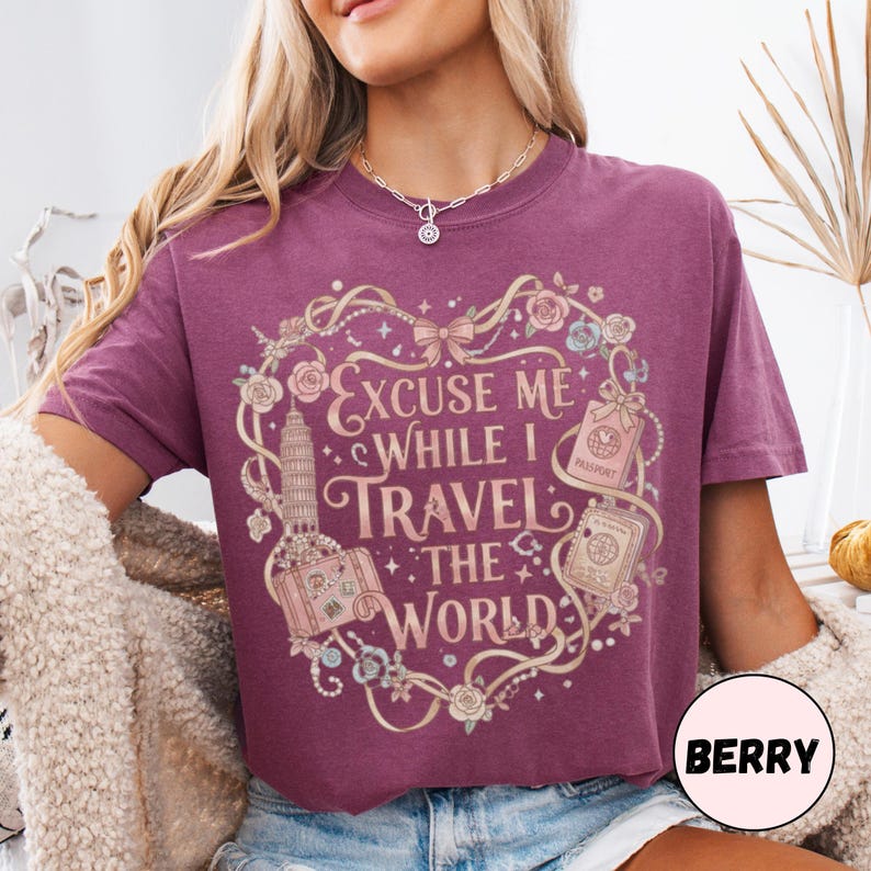 Vintage-inspired pink and beige travel-themed shirt with passport, suitcase, and the quote “Excuse Me While I Travel The World” framed in florals.