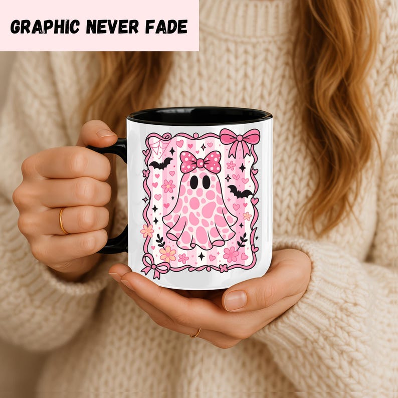 ceramic coffee mug featuring a pink spotted ghost with a bow, surrounded by bats, hearts, and flowers in a coquette aesthetic design