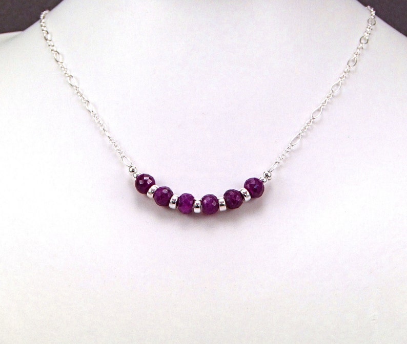 May include: A silver chain necklace with a row of purple gemstone beads.