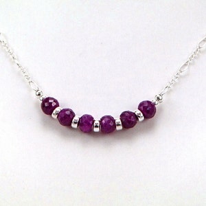 May include: A silver chain necklace with a row of purple gemstone beads.
