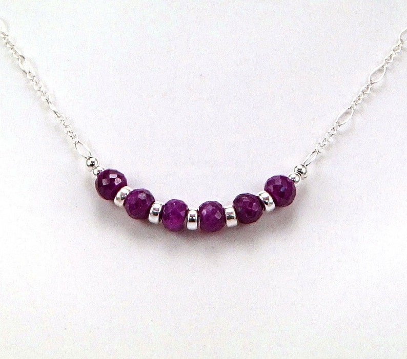 May include: A silver chain necklace with a row of purple gemstone beads.
