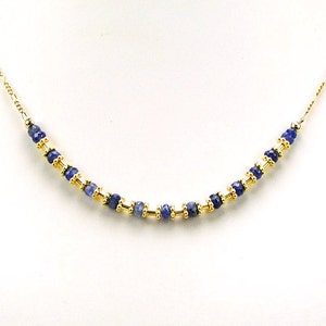 May include: A gold chain necklace with a row of blue gemstone beads.