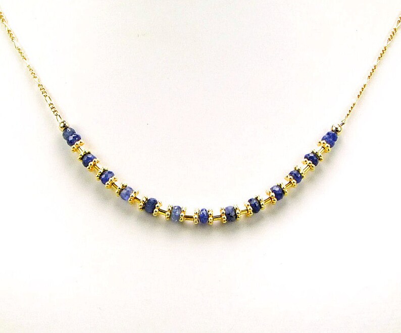 May include: A gold chain necklace with a row of blue gemstone beads.