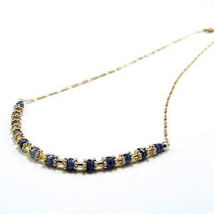 May include: A gold chain necklace with a row of dark blue gemstone beads.