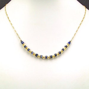 May include: A gold chain necklace with a row of blue gemstone beads.