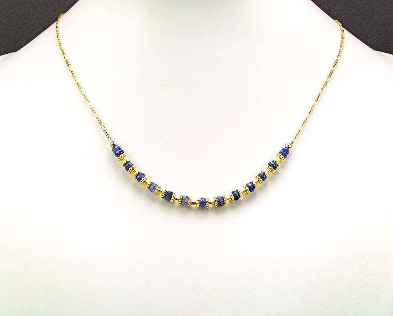 May include: A gold chain necklace with a row of blue gemstone beads.