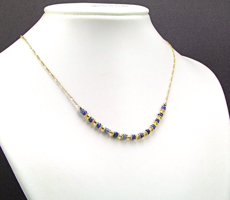 May include: A gold chain necklace with blue gemstone beads.