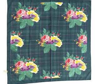 May include: A square, dark green scarf with a plaid design. The scarf has repeating floral bouquets in pink, yellow, and purple, with green leaves. The scarf is made of a soft fabric.