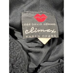 May include: Black dress with a black lace trim and a white tag. The tag says "climax for David Howard Karen Okada" with a red lip print.