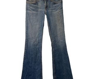 May include: Blue denim jeans with a flared leg. The jeans feature a classic five-pocket design, a button and zip fastening, and are suspended from a metal hanger. The denim has a faded wash effect.