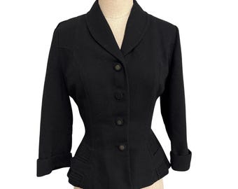 May include: A black blazer with a classic design. The jacket features a notched collar, three buttons, and three-quarter sleeves with folded cuffs. The waist is cinched, and the jacket has decorative details on the lower front.
