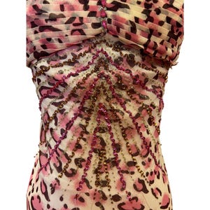 May include: A sleeveless dress with a pink and black leopard print pattern. The bodice is embellished with rows of pink and gold beads. The top of the dress has a pleated design with the same leopard print. The dress is made of a lightweight fabric.