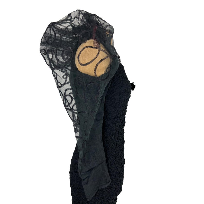 May include: Black lace overlay with a black textured fabric underneath. The lace has a swirl pattern.