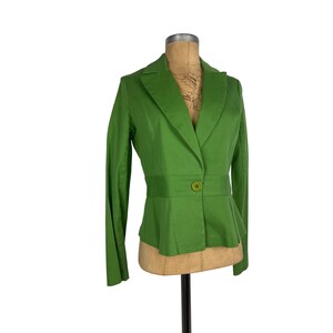 May include: A bright green blazer with a single-button closure and a fitted waist. The blazer is displayed on a mannequin and has long sleeves and a notched lapel. The fabric appears to be a solid color.