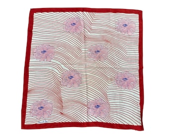 May include: Square silk scarf with a red border and a white background featuring red wavy lines and pink floral designs with blue centers. The scarf has a label in the bottom left corner.