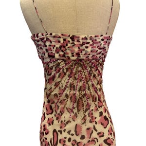 May include: A sleeveless dress with a pink and brown leopard print pattern. The bodice features a ruched design with a pink and brown pattern. The dress is embellished with pink and brown beads, and has thin spaghetti straps.
